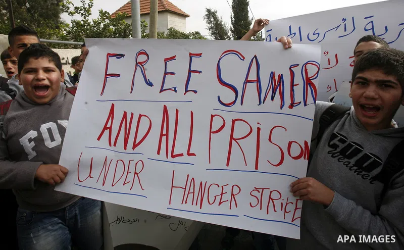 Relatives of Palestinians jailed in Israel demonstrate with placards of a detained prisoner, Tareq Issawi, who is on a hunger strike, as they protest for his release in Jerusalem, 27 November 2012. Photo by Mahfouz Abu T...