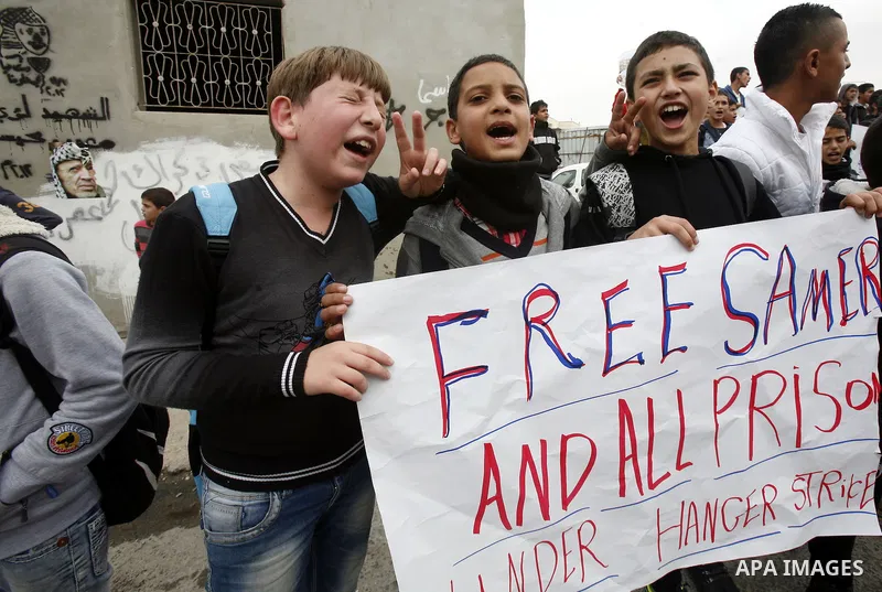 Relatives of Palestinians jailed in Israel demonstrate with placards of a detained prisoner, Tareq Issawi, who is on a hunger strike, as they protest for his release in Jerusalem, 27 November 2012. Photo by Mahfouz Abu T...