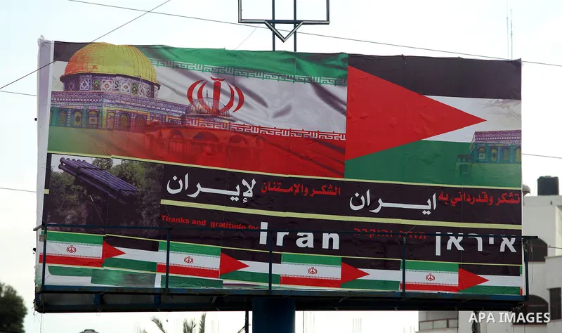 Palestinians walk next to a placard reads in Arabic "Thanks for Iran" in Gaza city on November 27, 2012. The commander of Iran's elite Revolutionary Guards has publicly admitted that his forces supplied the Islamic milit...