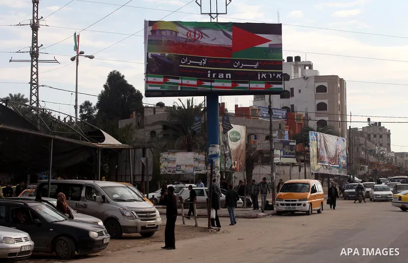 Palestinians walk next to a placard reads in Arabic "Thanks for Iran" in Gaza city on November 27, 2012. The commander of Iran's elite Revolutionary Guards has publicly admitted that his forces supplied the Islamic milit...