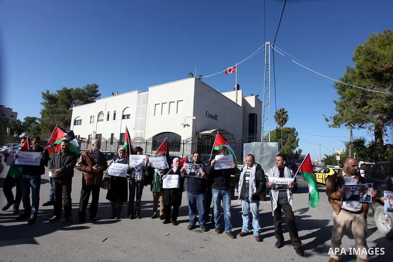 Palestinians hold national flags and a poster of Canadian Prime Minister Stephen Harper superimposed with a face of a dog during a protest following his remarks about the Palestinian UN bid for an observer state status,...
