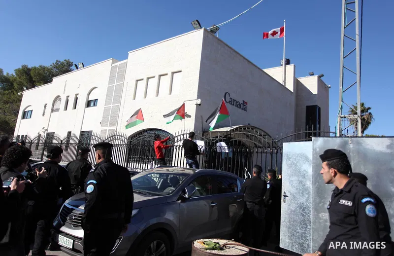 Palestinian activists hoist the Palestinian flag on top the Canadian representative office fence during a protest following his remarks about the Palestinian UN bid for an observer state status, in front of Canadian repr...