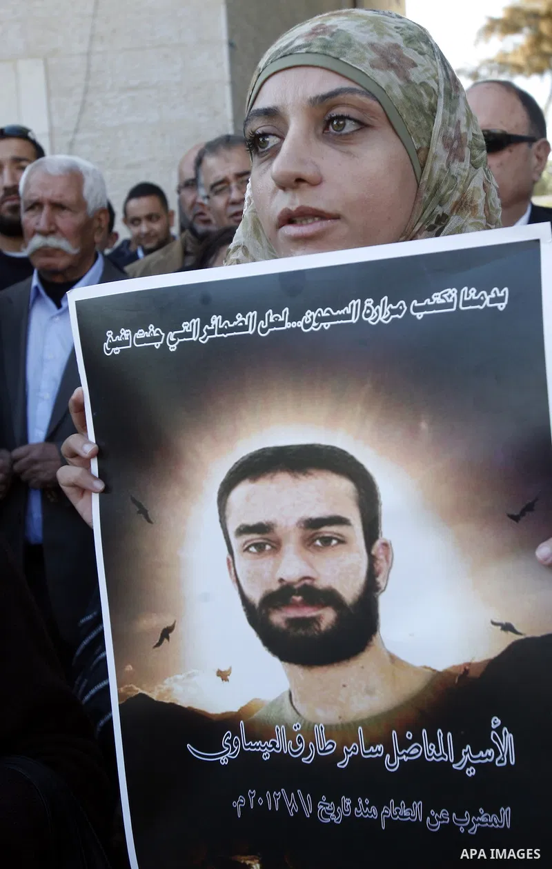 Palestinian protesters hold portraits of Samer Issawi, a Palestinian prisoner held in an Israeli jail and on hunger strike since August 1, during a solidarity sit-in outside the Red Cross offices in Jerusalem, on Novembe...
