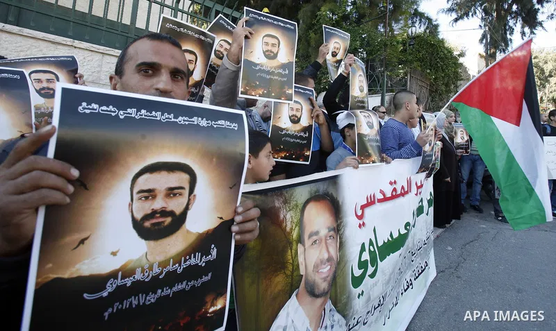 Palestinian protesters hold portraits of Samer Issawi, a Palestinian prisoner held in an Israeli jail and on hunger strike since August 1, during a solidarity sit-in outside the Red Cross offices in Jerusalem, on Novembe...