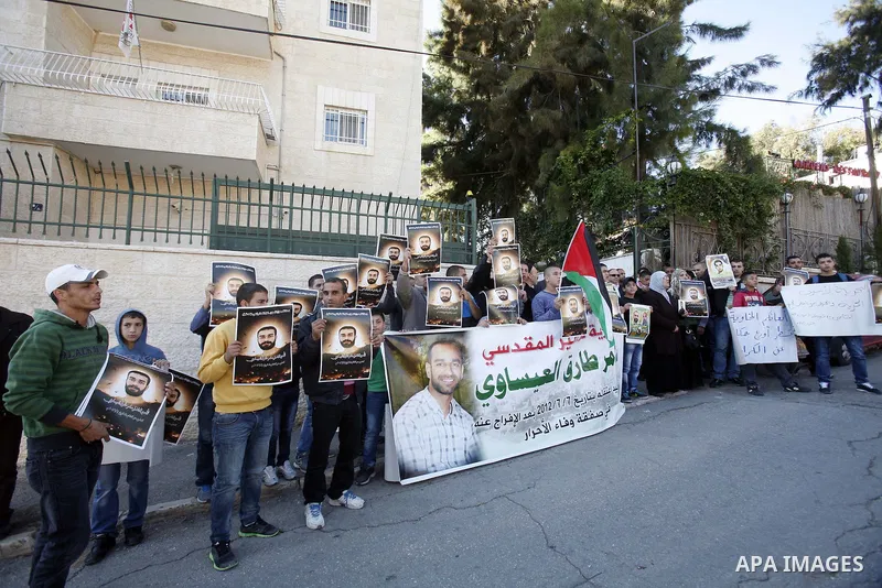 Palestinian protesters hold portraits of Samer Issawi, a Palestinian prisoner held in an Israeli jail and on hunger strike since August 1, during a solidarity sit-in outside the Red Cross offices in Jerusalem, on Novembe...