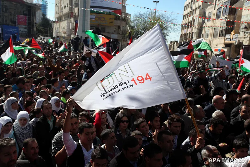 Palestinians wave their national flag during a rally in the West Bank city of Ramallah on November 29, 2012 to support Palestinian leader Mahmud Abbas who is heading to the United Nations General Assembly today with huge...