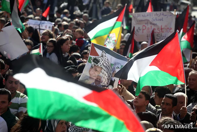 Palestinians wave their national flag during a rally in the West Bank city of Ramallah on November 29, 2012 to support Palestinian leader Mahmud Abbas who is heading to the United Nations General Assembly today with huge...