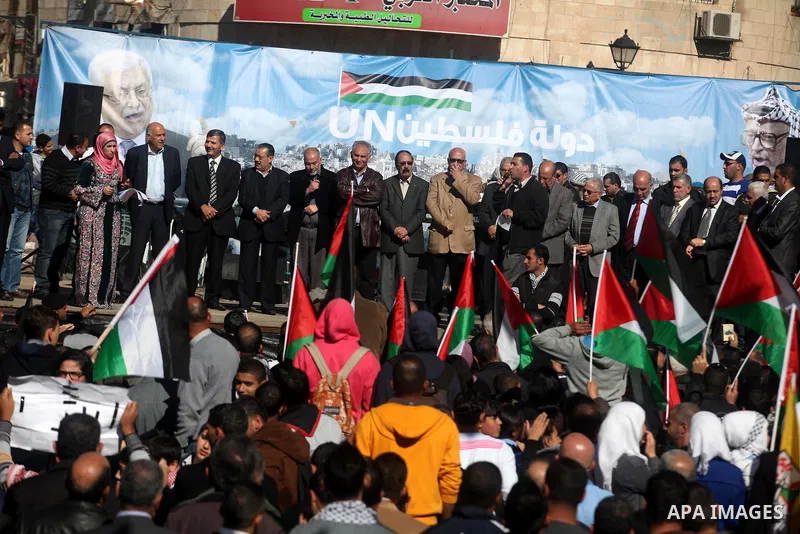Palestinians wave their national flag during a rally in the West Bank city of Ramallah on November 29, 2012 to support Palestinian leader Mahmud Abbas who is heading to the United Nations General Assembly today with huge...