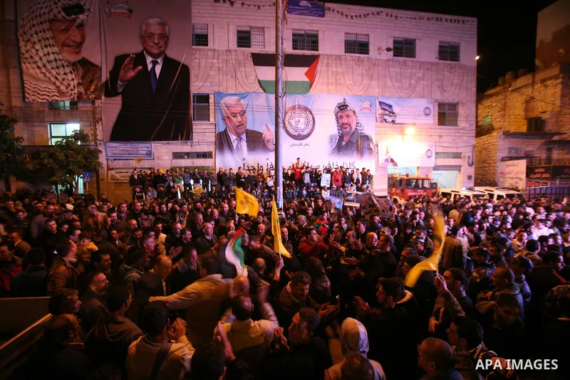 Palestinians wave their national flag during the speech of President Mahmoud Abbas in the U.N. General Assembly, in the West Bank city of Hebron, November 29, 2012. The 193-nation U.N. General Assembly overwhelmingly app...