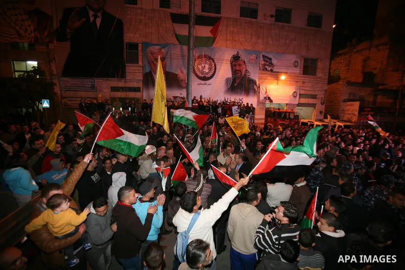 Palestinians wave their national flag during the speech of President Mahmoud Abbas in the U.N. General Assembly, in the West Bank city of Hebron, November 29, 2012. The 193-nation U.N. General Assembly overwhelmingly app...