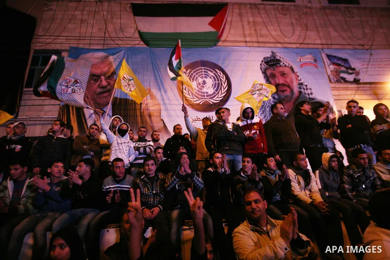 Palestinians wave their national flag during the speech of President Mahmoud Abbas in the U.N. General Assembly, in the West Bank city of Hebron, November 29, 2012. The 193-nation U.N. General Assembly overwhelmingly app...
