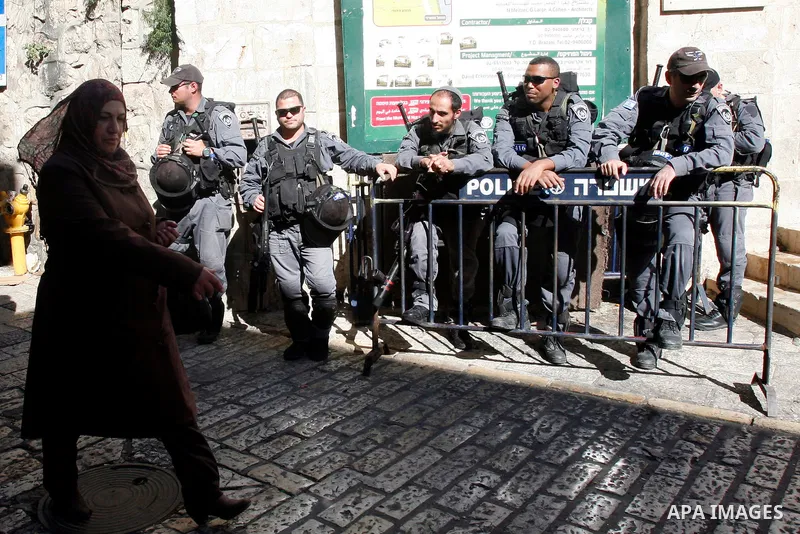 A Palestinian woman walks pass Israeli police officers following the Friday prayers in al-Aqsa mosque, in Jerusalem old city on November 30, 2012. Photo by Mahfouz Abu Turk