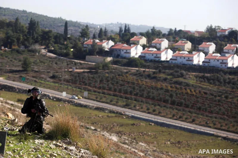 A Palestinian protester hurls a stone at Israeli security forces during a protest against the expansion of the nearby Jewish settlement of Halamish, in the West Bank village of Nabi Saleh near Ramallah, Friday, Nov. 30,...