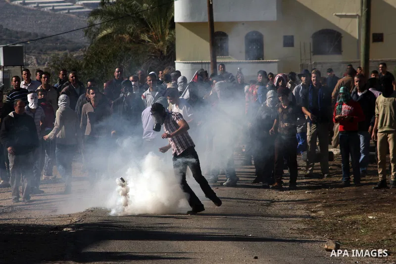 A Palestinian protester kicks a tear gas canister at Israeli soldiers on the sidelines of a demonstration against the expropriations by Israel in the West Bank village of Kafr Qaddum, near Nablus, on November 30, 2012. P...