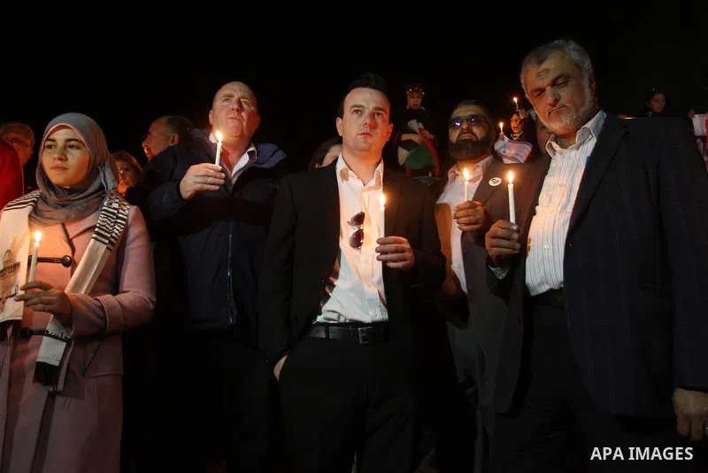Palestinian and foreign activists hold candles during a solidarity march with the Dalu family next to their house, as well as a wrecked car festooned with candles, which was hit by an Israeli strike during Israel's recen...