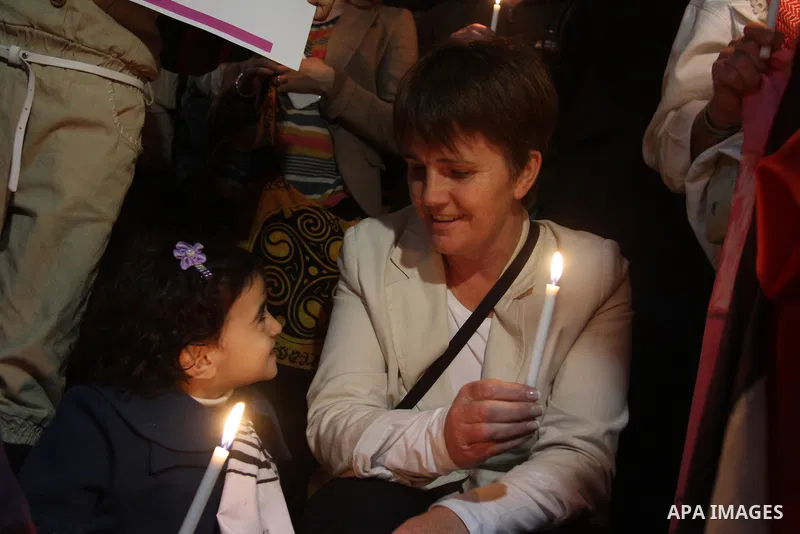 Palestinian and foreign activists hold candles during a solidarity march with the Dalu family next to their house, as well as a wrecked car festooned with candles, which was hit by an Israeli strike during Israel's recen...