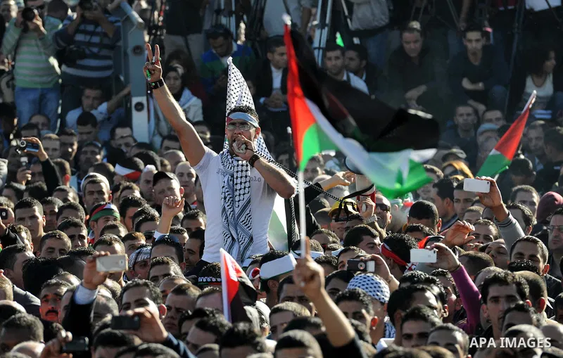 Palestinians wave national flags as they celebrate their successful bid for UN non-member observer state status, in the West Bank city of Ramallah on December 2, 2012, Palestinian President Mahmoud Abbas arrived to the W...