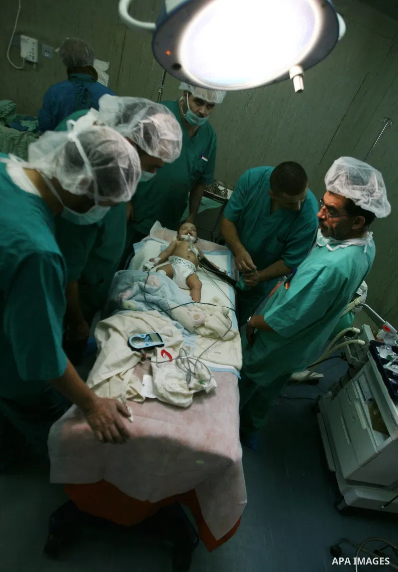 Palestinian and foreign doctors gather around a child who suffer from harelip and cleft palate during surgery operation at Hebron Governmental Hospital in the West Bank city of Hebron on December 2,2012. . Photo by Mamou...