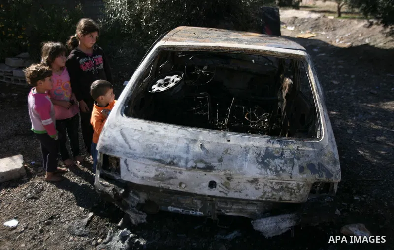 Palestinian children look at the car burned by Israeli settlers in the West Bank city of Hebron, on Dec.03, 2012. Photo by Mamoun Wazwaz