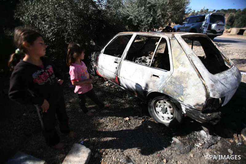Palestinian children look at the car burned by Israeli settlers in the West Bank city of Hebron, on Dec.03, 2012. Photo by Mamoun Wazwaz