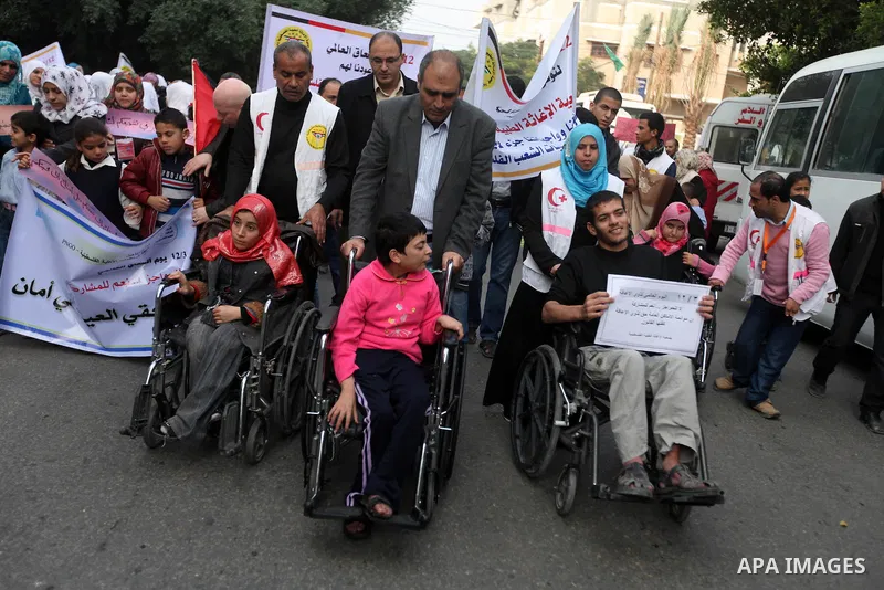 Palestinian children with special needs walk past buildings destroyed during the Gaza-Israeli conflict during a demonstration on the occasion of the UN International Day of People with Disability, on December 4, 2012 in...
