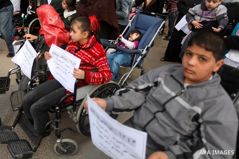 Palestinian children with special needs walk past buildings destroyed during the Gaza-Israeli conflict during a demonstration on the occasion of the UN International Day of People with Disability, on December 4, 2012 in...