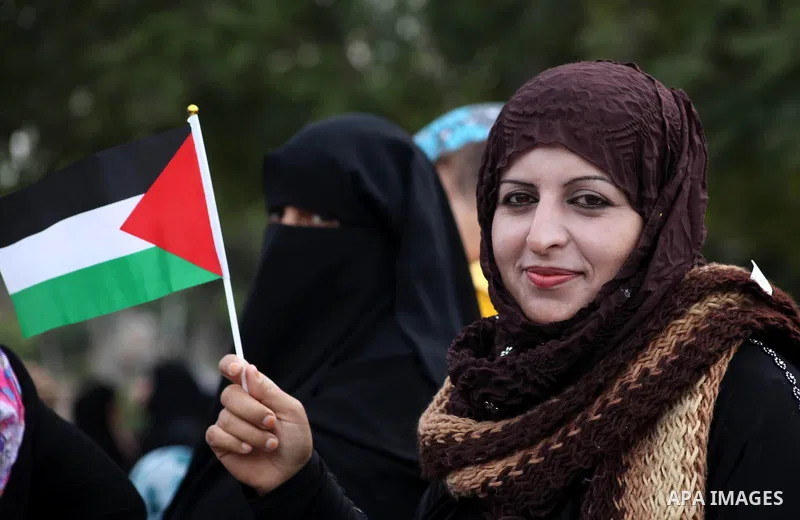 A Palestinian woman holds national flags during a rally to support reconciliation between rival Palestinian factions in Gaza city on 04 Dec, 2012. Palestinian President Mahmud Abbas pledged Sunday to resume efforts at re...