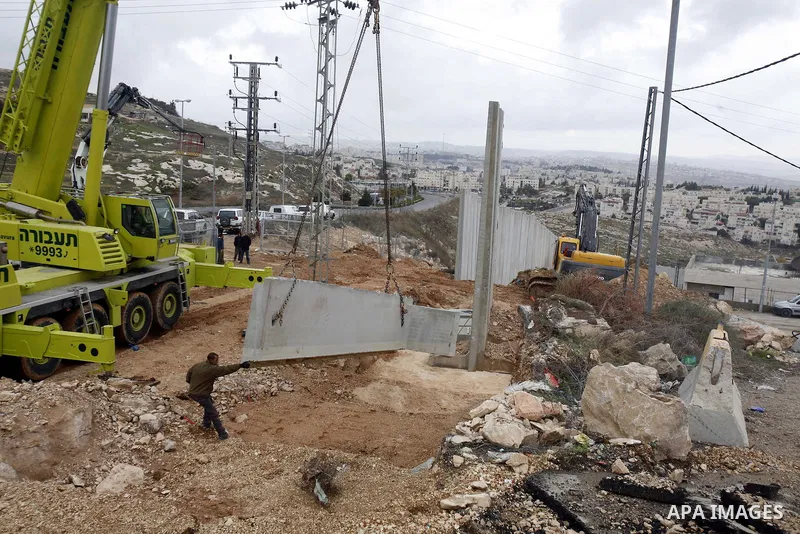Israeli laborers install concrete sections during the construction of the separation barrier wall in the Palestinian neighborhood of Shuafat in East Jerusalem, 05 Dec, 2012. Photo by Mahfouz Abu Turk