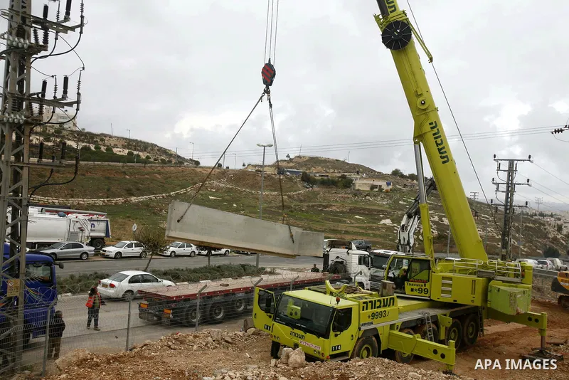 Israeli laborers install concrete sections during the construction of the separation barrier wall in the Palestinian neighborhood of Shuafat in East Jerusalem, 05 Dec, 2012. Photo by Mahfouz Abu Turk