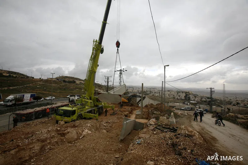 Israeli laborers install concrete sections during the construction of the separation barrier wall in the Palestinian neighborhood of Shuafat in East Jerusalem, 05 Dec, 2012. Photo by Mahfouz Abu Turk