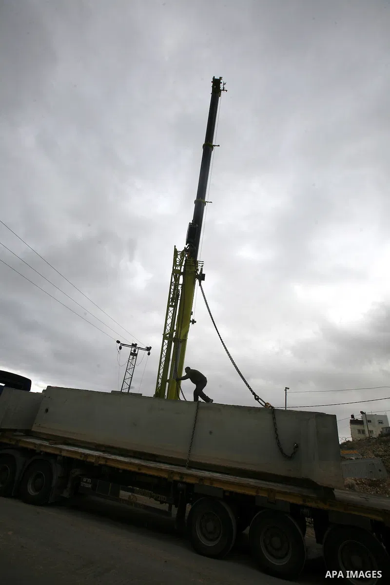 Israeli laborers install concrete sections during the construction of the separation barrier wall in the Palestinian neighborhood of Shuafat in East Jerusalem, 05 Dec, 2012. Photo by Mahfouz Abu Turk