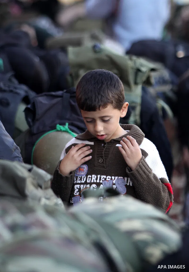 A Palestinian boy attends Friday prayer next to members of the Ezzedine al-Qassam brigade, the armed wing Hamas, as they prepare for the arrival of the Islamist movement's exiled politburo chief Khaled Meshaal who is due...