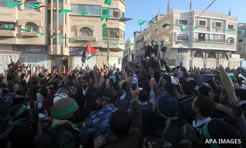 Hamas chief Khaled Meshaal, riding in a car with Palestinian prime minister in Gaza Strip Ismail Haniyeh, waves to the crowd upon his arrival in Gaza City December 7, 2012. Meshaal is making his first-ever visit to the G...