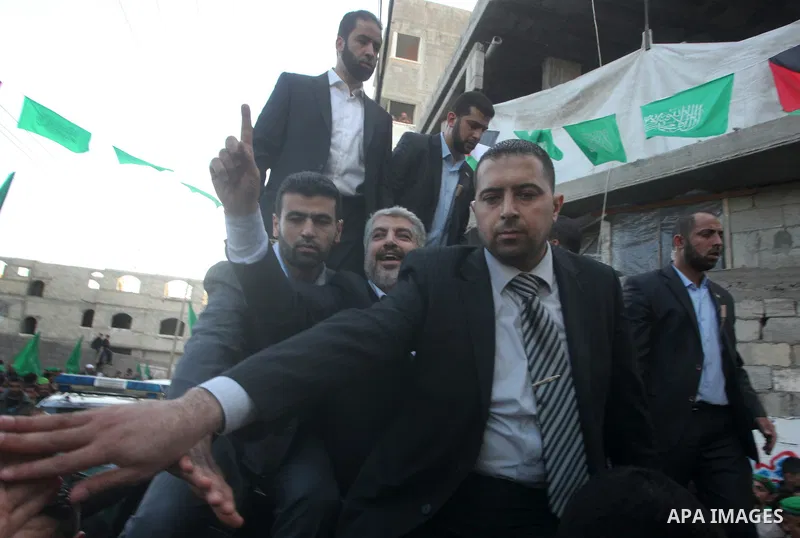 Hamas chief Khaled Meshaal, riding in a car with Palestinian prime minister in Gaza Strip Ismail Haniyeh, waves to the crowd upon his arrival in Gaza City December 7, 2012. Meshaal is making his first-ever visit to the G...