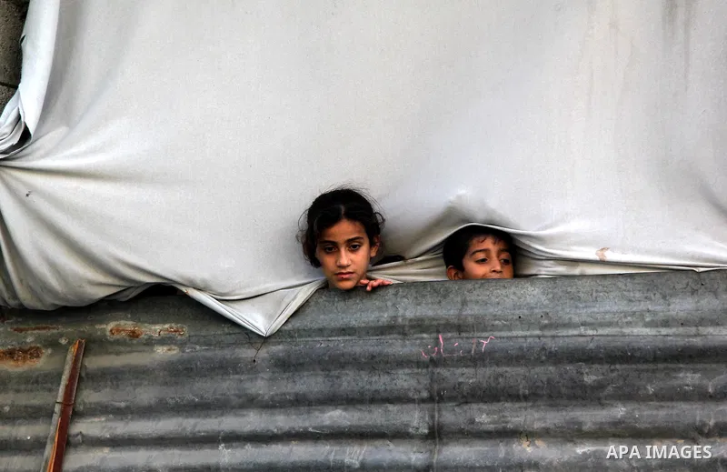 Palestinian children watch as Hamas chief Khaled Meshaal arrives in Gaza City December 7, 2012. Meshaal is making his first-ever visit to the Gaza Strip amid tight security for festivities marking the ruling Islamist mov...