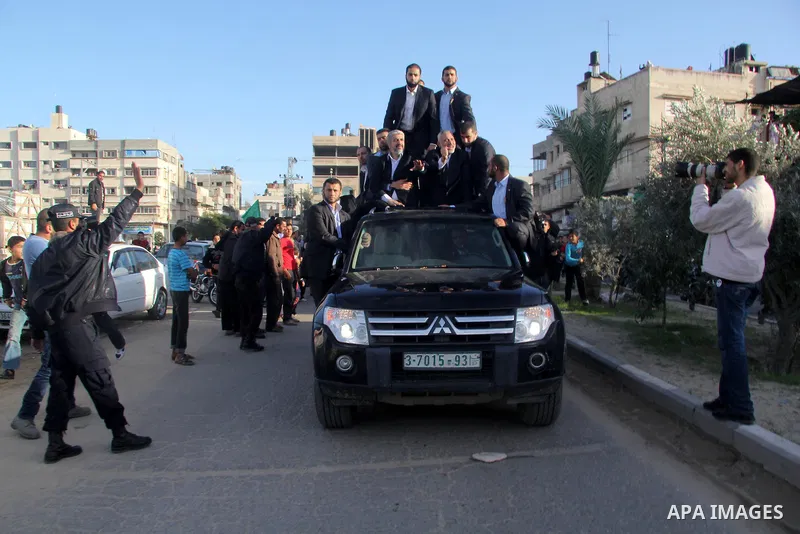 Hamas chief Khaled Meshaal, riding in a car with Palestinian prime minister in Gaza Strip Ismail Haniyeh, waves to the crowd upon his arrival in Gaza City December 7, 2012. Meshaal is making his first-ever visit to the G...