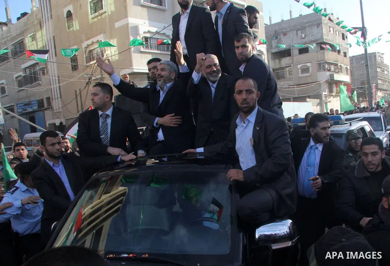 Hamas chief Khaled Meshaal, riding in a car with Palestinian prime minister in Gaza Strip Ismail Haniyeh, waves to the crowd upon his arrival in Gaza City December 7, 2012. Meshaal is making his first-ever visit to the G...