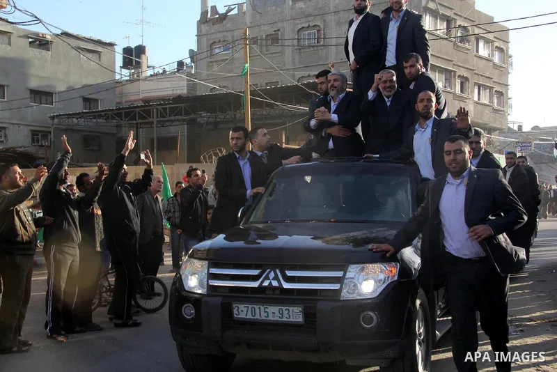 Hamas chief Khaled Meshaal, riding in a car with Palestinian prime minister in Gaza Strip Ismail Haniyeh, waves to the crowd upon his arrival in Gaza City December 7, 2012. Meshaal is making his first-ever visit to the G...