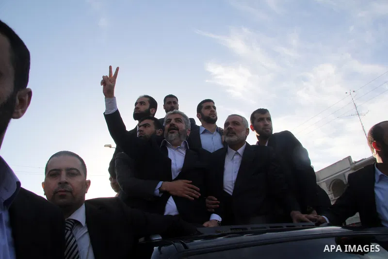 Hamas chief Khaled Meshaal, riding in a car with Palestinian prime minister in Gaza Strip Ismail Haniyeh, waves to the crowd upon his arrival in Gaza City December 7, 2012. Meshaal is making his first-ever visit to the G...