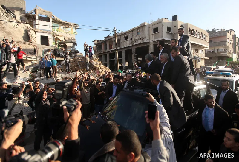 Hamas chief Khaled Meshaal, riding in a car with Palestinian prime minister in Gaza Strip Ismail Haniyeh, waves to the crowd upon his arrival in Gaza City December 7, 2012. Meshaal is making his first-ever visit to the G...