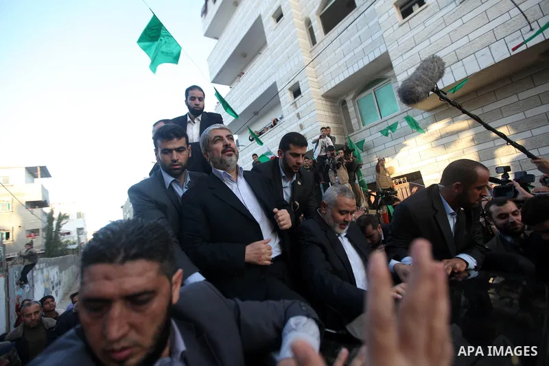 Hamas chief Khaled Meshaal, riding in a car with Palestinian prime minister in Gaza Strip Ismail Haniyeh, waves to the crowd upon his arrival in Gaza City December 7, 2012. Meshaal is making his first-ever visit to the G...