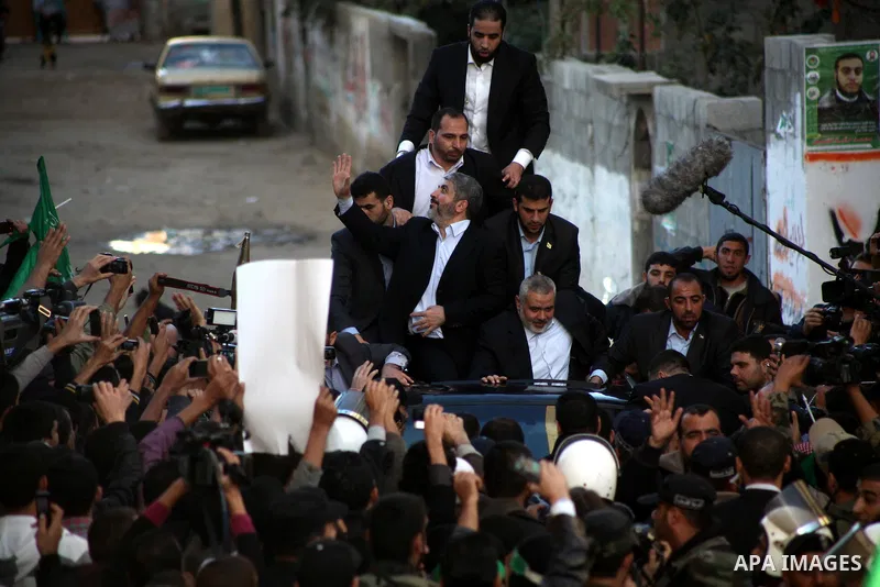 Hamas chief Khaled Meshaal, riding in a car with Palestinian prime minister in Gaza Strip Ismail Haniyeh, waves to the crowd upon his arrival in Gaza City December 7, 2012. Meshaal is making his first-ever visit to the G...
