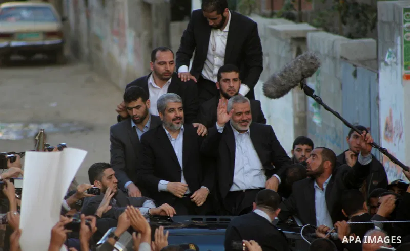 Hamas chief Khaled Meshaal, riding in a car with Palestinian prime minister in Gaza Strip Ismail Haniyeh, waves to the crowd upon his arrival in Gaza City December 7, 2012. Meshaal is making his first-ever visit to the G...