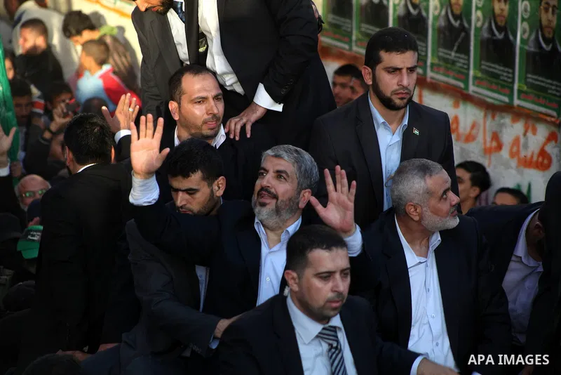 Hamas chief Khaled Meshaal, riding in a car with Palestinian prime minister in Gaza Strip Ismail Haniyeh, waves to the crowd upon his arrival in Gaza City December 7, 2012. Meshaal is making his first-ever visit to the G...