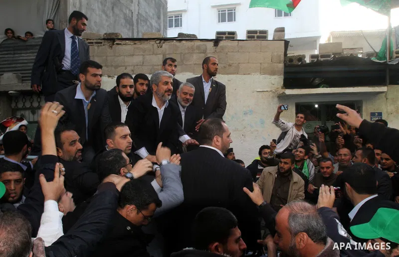 Hamas chief Khaled Meshaal, riding in a car with Palestinian prime minister in Gaza Strip Ismail Haniyeh, waves to the crowd upon his arrival in Gaza City December 7, 2012. Meshaal is making his first-ever visit to the G...