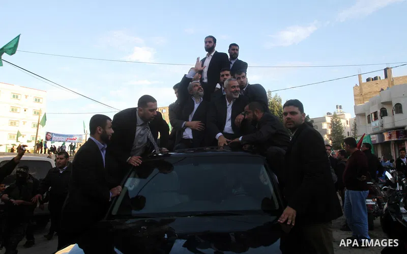 Hamas chief Khaled Meshaal, riding in a car with Palestinian prime minister in Gaza Strip Ismail Haniyeh, waves to the crowd upon his arrival in Gaza City December 7, 2012. Meshaal is making his first-ever visit to the G...