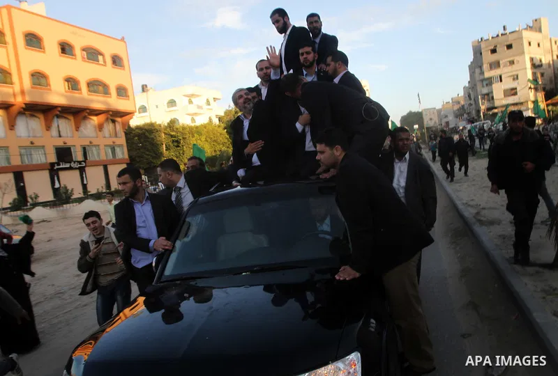 Hamas chief Khaled Meshaal, riding in a car with Palestinian prime minister in Gaza Strip Ismail Haniyeh, waves to the crowd upon his arrival in Gaza City December 7, 2012. Meshaal is making his first-ever visit to the G...