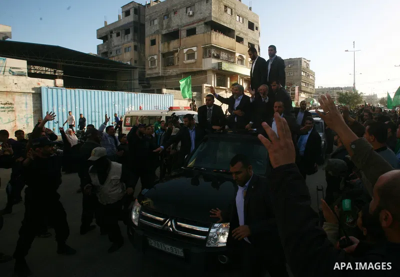 Hamas chief Khaled Meshaal, riding in a car with Palestinian prime minister in Gaza Strip Ismail Haniyeh, waves to the crowd upon his arrival in Gaza City December 7, 2012. Meshaal is making his first-ever visit to the G...
