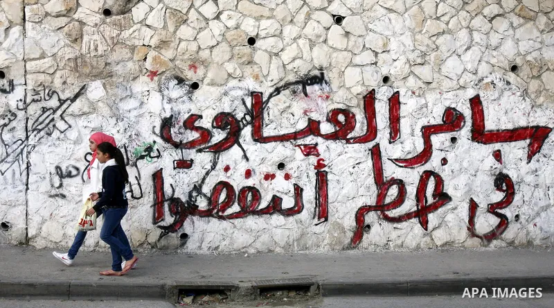 Palestinian girls walk past a wall depicting the name Palestinian prisoner Samer Issawi who is on a hunger strike, in the Jerusalem on December 7, 2012. Photo by Mahfouz Abu Turk
