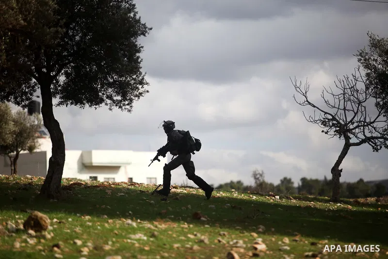 An Israeli soldier fires tear gas towards Palestinian protesters during clashes following a demonstration against the expropriation of Palestinian land by Israel in the West Bank village of Nabi Saleh on December 7, 2012...